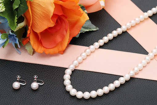 Elegant white pearl necklace and earrings on black background