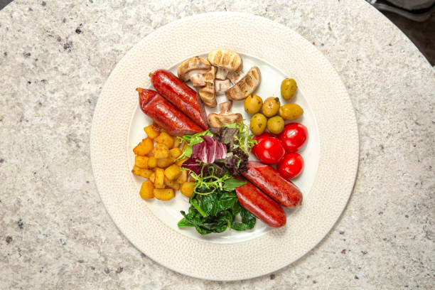 English breakfast with sausages, mushrooms, tomato, potato, olive and salad. Above.