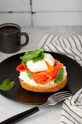 Healthy breakfast, sandwich with creme cheese, salmon, spinach and poached egg.