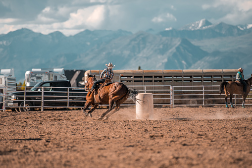 Young Cowboy riding a horse in a rodeo arena. About to barrel race.