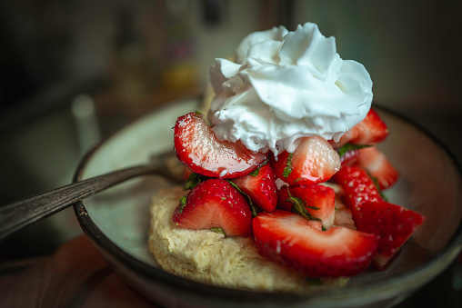Strawberry shortcake in a ceramic bowl with a fork, close up