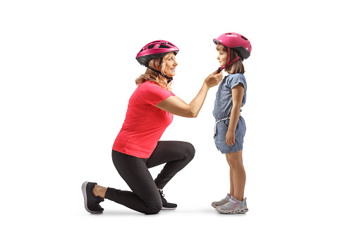 Mother putting a helmet on a child solated on white background