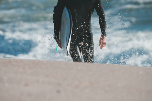 istock Surfer in winter wetsuit walking with the surfboard 1497755495