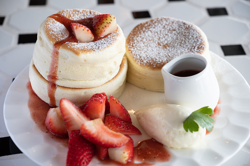 A plate of strawberry souffle pancake served with strawberry sauce and ice cream.