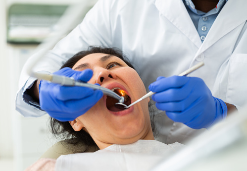 Asian woman sitting on dental chair with opened mouth and waiting for medical procedures ending in dentistry clinic.