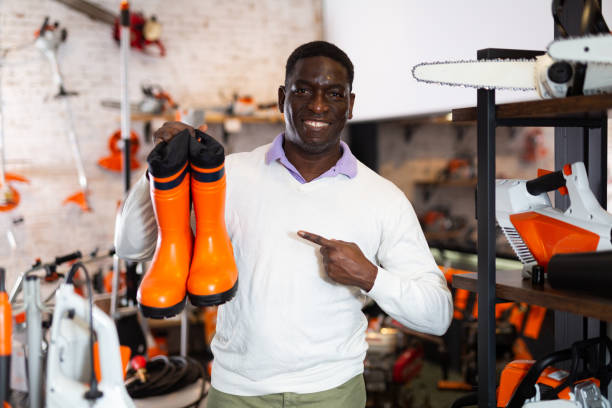 Man with new boots in gardening tools store African-american man standing in gardening tools store with pair of boots in hands and pointing finger at it. kenyan man stock pictures, royalty-free photos & images