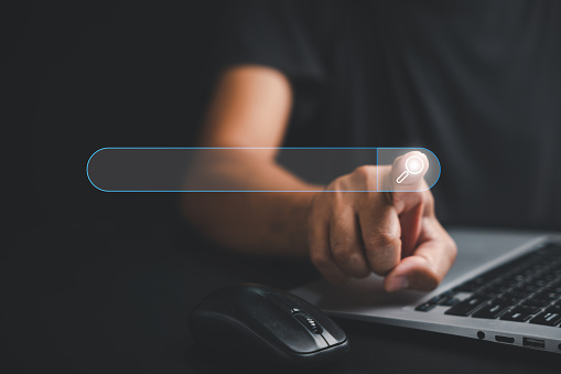 Businessman's hand touches the button of a blank search bar on a business web banner promoting the concept of search engine optimization. digital screen importance of SEO in the world technology.