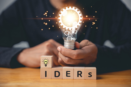 Question and solution concept. Person holding wooden block with light bulb icon, suggesting an answer with copy space. Innovation and problem-solving for corporate success. new ideas