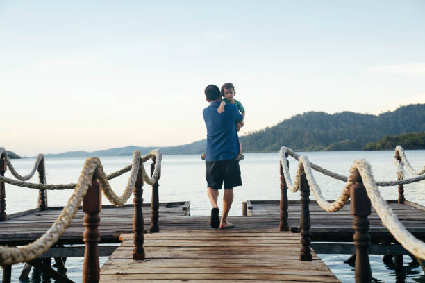 istock father carrying son on jetty at sunrise 1497763513