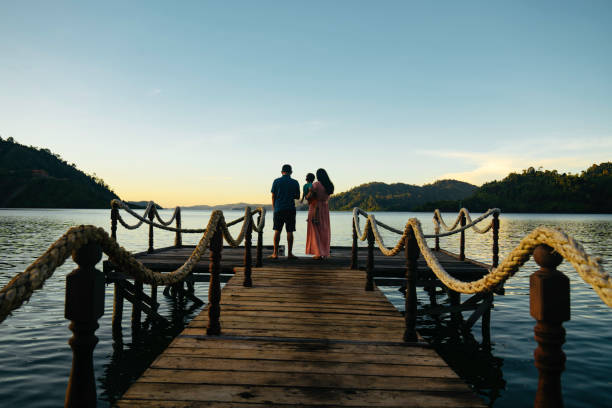 istock Asian couple carrying son on jetty at sunrise, 1497763601