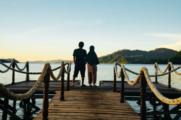 istock Asian couple standing on jetty at sunrise 1497763633