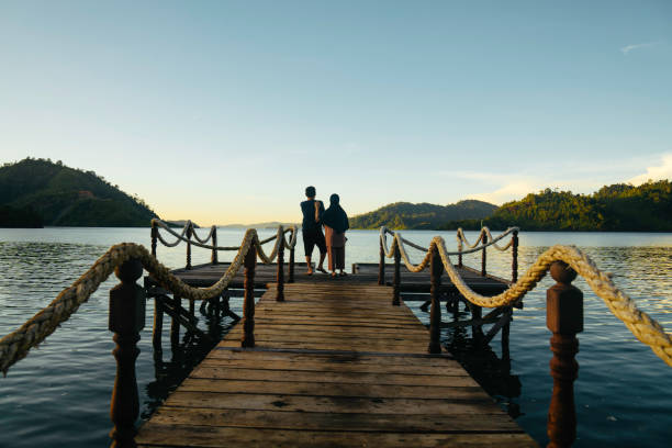 istock Asian couple standing on jetty at sunrise 1497763644