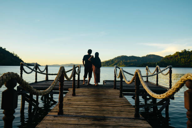 istock Asian couple standing on jetty at sunrise 1497763646