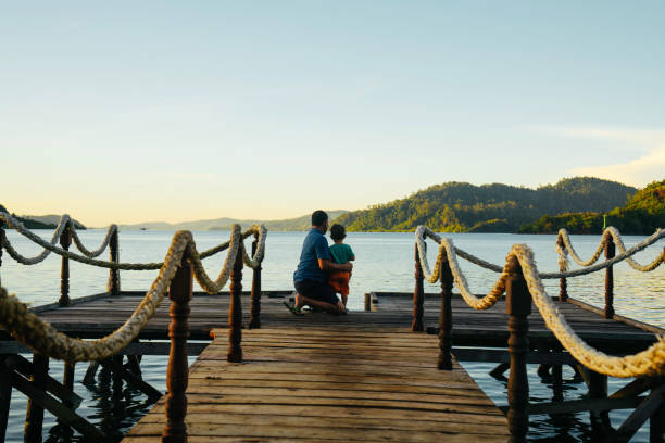 istock father carrying son on jetty at sunrise 1497763661