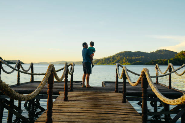 istock father carrying son on jetty at sunrise 1497763662