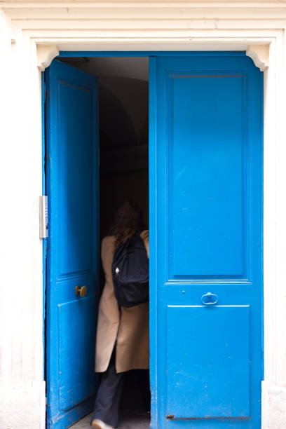 Grenoble, France: A young woman entering old blue doors in old town Grenoble.