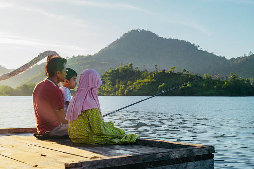 asian muslim family fishing together at terusan mande, painan, west sumatra