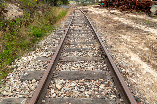 Photograph of old and rusty and out of service railway tracks with white stones and dead weeds