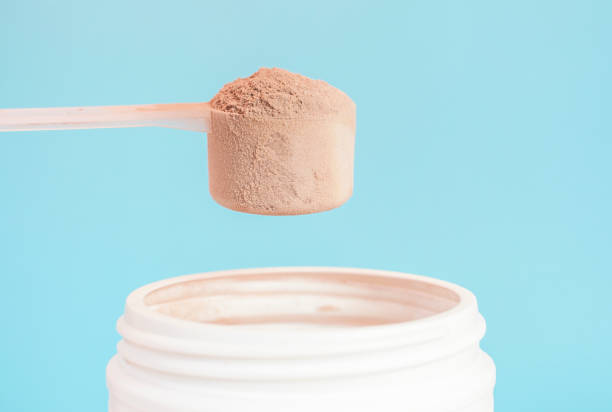 istock Chocolate protein powder in scoop and plastic jar on blue background. 1497765950