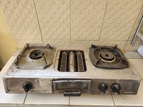 Stock photo showing close-up, elevated view of modern kitchen island with five ring burner gas hob stovetop. White stone, Corian kitchen worktop with under counter storage draws.