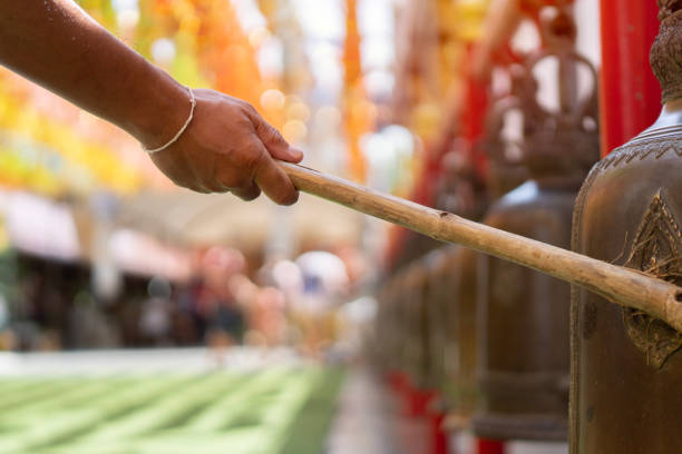 nahaufnahme des asiatischen mannes, der in den alten goldenen glocken oder korridoren eines tempels läutet - iron asian culture buddhism buddha stock-fotos und bilder