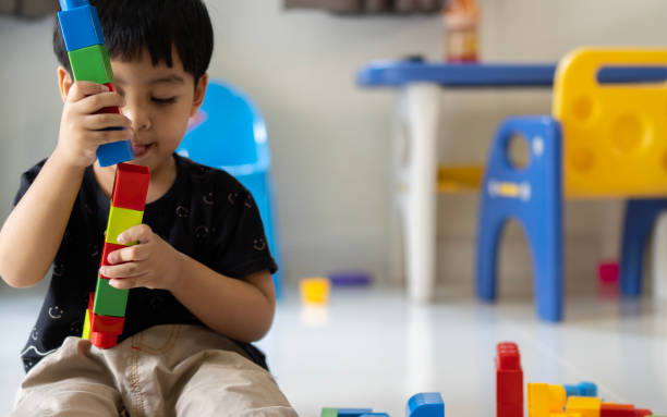 un garçon asiatique de trois ans construit des figurines à partir de grandes pièces en plastique avec intérêt et enthousiasme. - early childhood education photos et images de collection