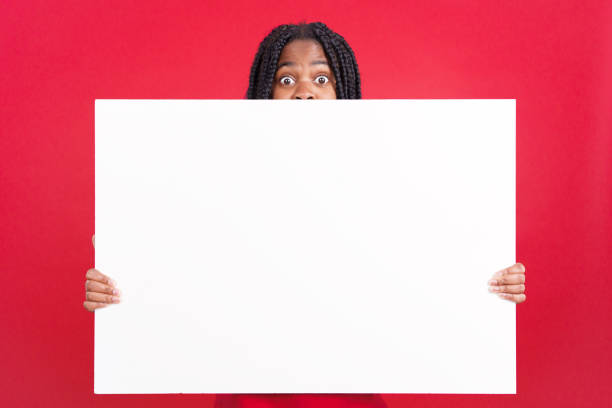 istock Surprised african woman hiding behind a blank panel 1497779318