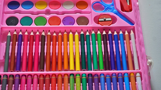 Neatly organized group of colorful pencils and color pastels for education template background