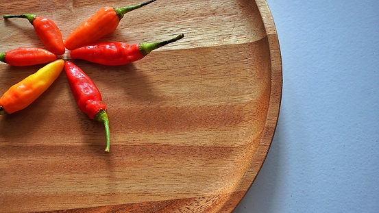 Isolated flat lay cayenne pepper or Capsicum annuum also commonly called Bird's Eye on a wooden tray. Selective focus