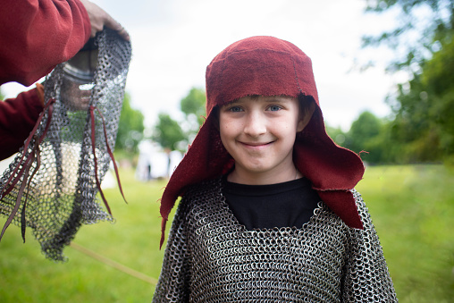 child in chain mail and headdress of the middle ages in the park