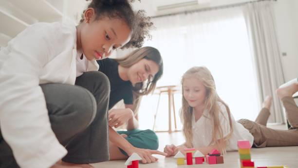 istock Teacher or nanny take care cute kids playing with plastic building blocks. Elementary students learning about intellectual games in classroom. Multiracial group of children playing with toy blocks set together. Activities to enhance imagination. Education 1497783474