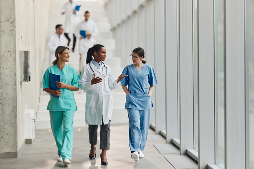 Happy female medical experts communicating while walking in a hallway of a hospital.