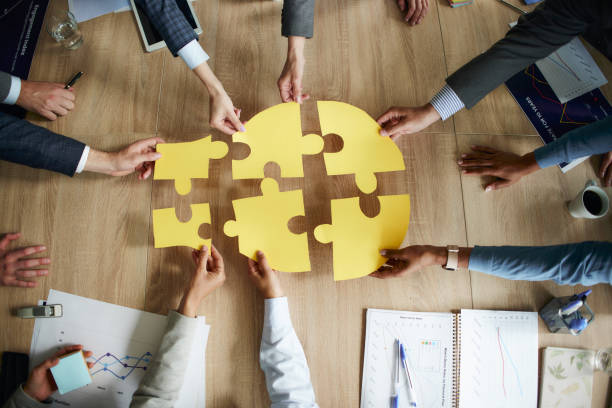 Perfect connection on business meeting! High angle view of unrecognizable business team connecting puzzles on a meeting in the office. mergers and acquisitions stock pictures, royalty-free photos & images