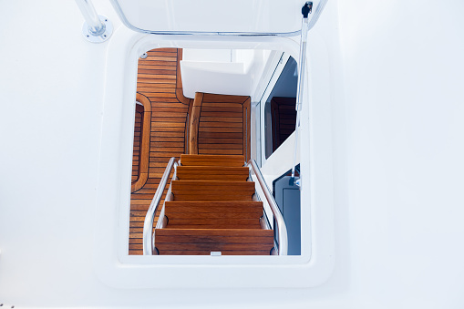 Teak steps and part of the deck, on a luxury yacht with stainless steel handrails.