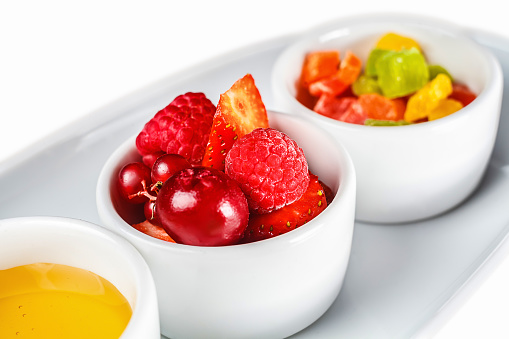 A white plate topped with two bowls filled with fruit