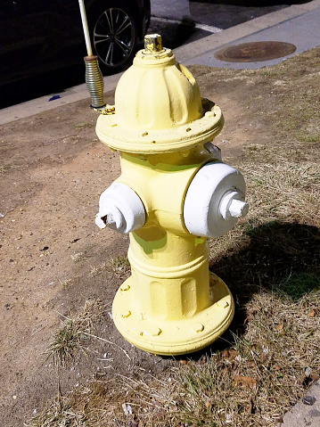 Yellow fire hydrant by four-lane street  gushing water on a winter day