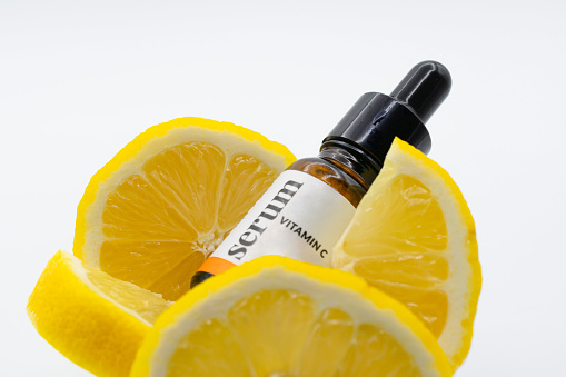Facial serum in a glass bottle with vitamin C. A cosmetic product with a natural ingredient for all ages. Top view
