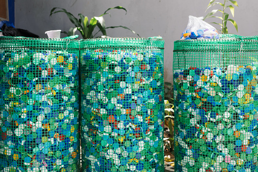 DIY mesh containers holding hundreds of plastic bottle caps at a recycling facility