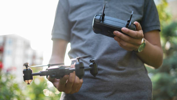 giovane maschio irriconoscibile che tiene il drone e il telecomando - corsa di droni immagine foto e immagini stock
