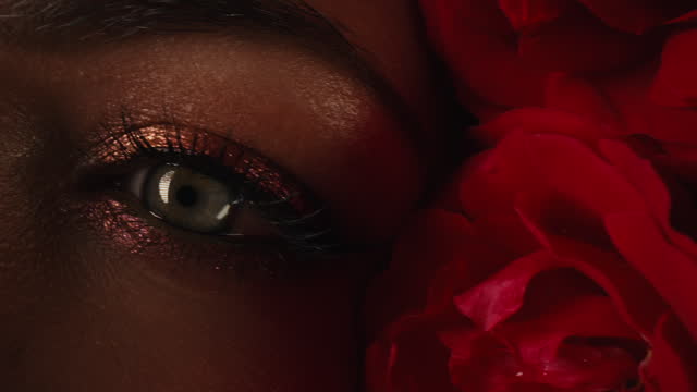 Beautiful woman eyes with vibrant make-up in roses flowers bath. Skin care concept