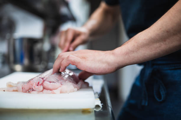 istock Side view of a cook's hands cutting angler fish in a restaurant. 1497806534