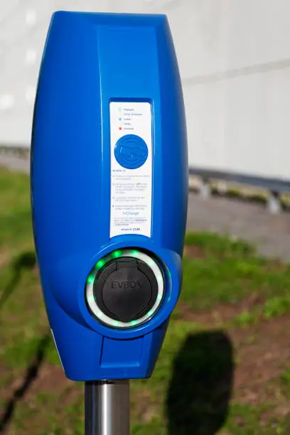 Umea, Sweden - July 27, 2019: blue pole to charge electric cars with outside Volvo