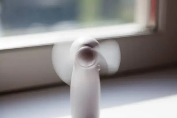 a small white table fan that stands in the windowsill when it is warm outside and indoors