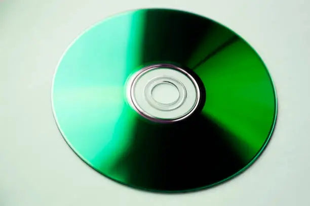 a dvd disc that looks green in the sunlight from windows is on white background