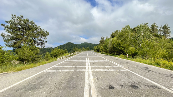 Asphalt road in the mountains under blue sky with white clouds.
