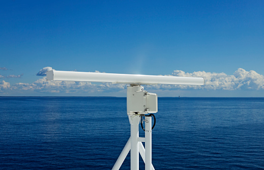 a white rotating radar on a large ship at sea