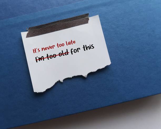 istock Stick torn note on blue text books with text written I AM TOO OLD FOR THIS, changed to IT IS NEVER TOO LATE FOR THIS - to replace negative self criticism to positive self talk with growth mindset 1497807801