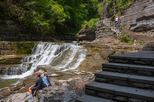 Ithaca, NY, USA - Jun 11, 2023: A couple observes the rapids of Lucifer Falls at Robert H. Treman State Park located in the Finger Lakes Region of New York State during a summer afternoon.