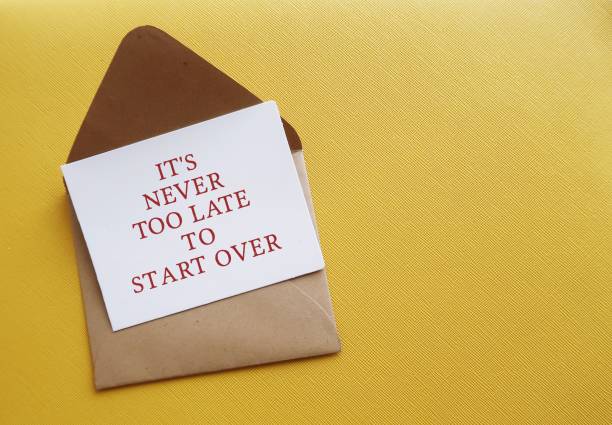 Envelope on copy space yellow background with handwritten card - It's never too late to start over - means to get out of a rut in career path, relationship or unhealthy habit, embrace new beginnings sobre en el espacio de copia fondo amarillo con tarjeta escrita a mano - nunca es demasiado tarde para empezar de nuevo - significa salir de una rutina en la trayectoria profesional, la relación o el hábito poco saludable, abrazar nuevos comienzos