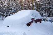 A large snow cap on the car - a car buried by snow powder